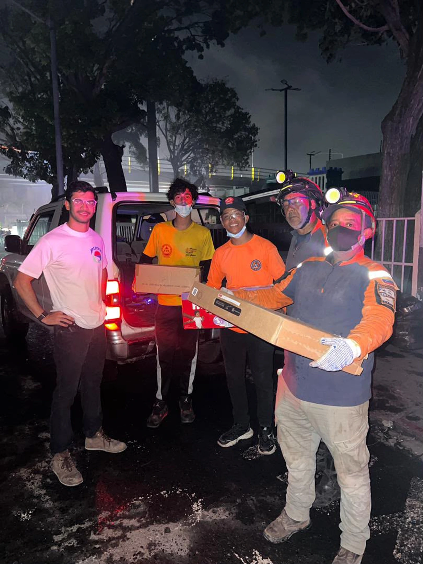 Relief volunteers receiving Starlink equipment beside a pickup at night in Venezuela